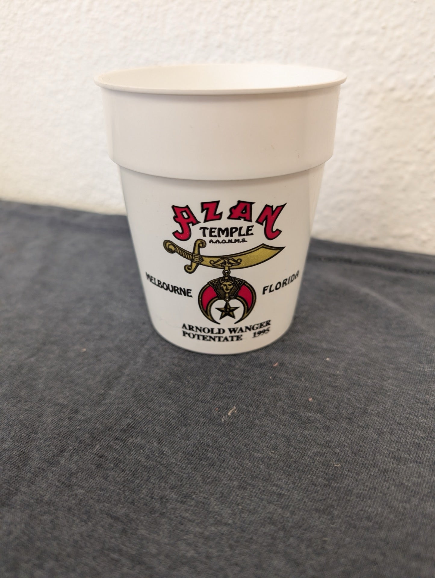 Small white plastic cup with a red and gold Shriners Azan Temple logo from 1995.