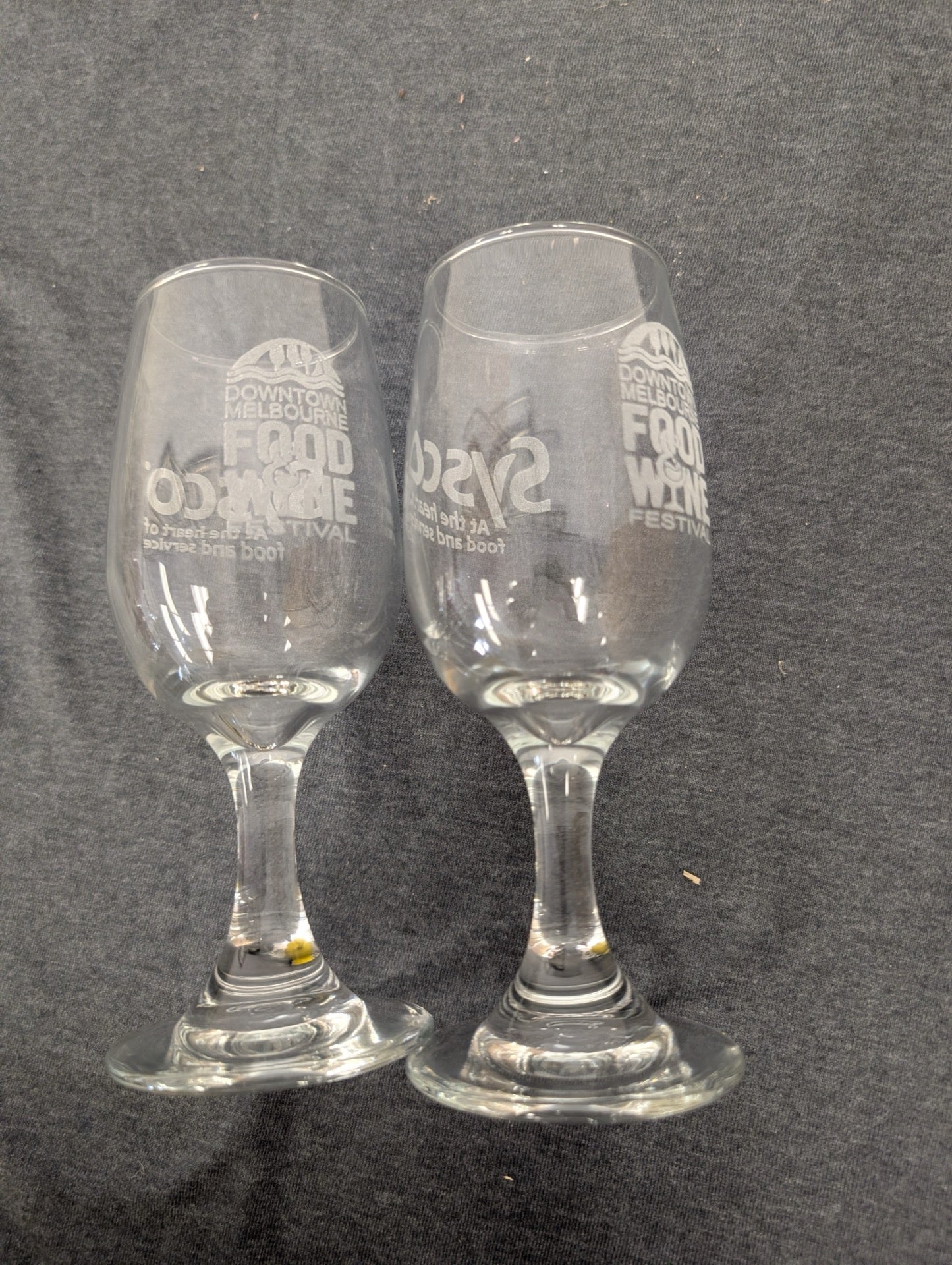 Two clear stemmed wine tasting glasses etched with the Downtown Melbourne Food and Wine Festival logo.