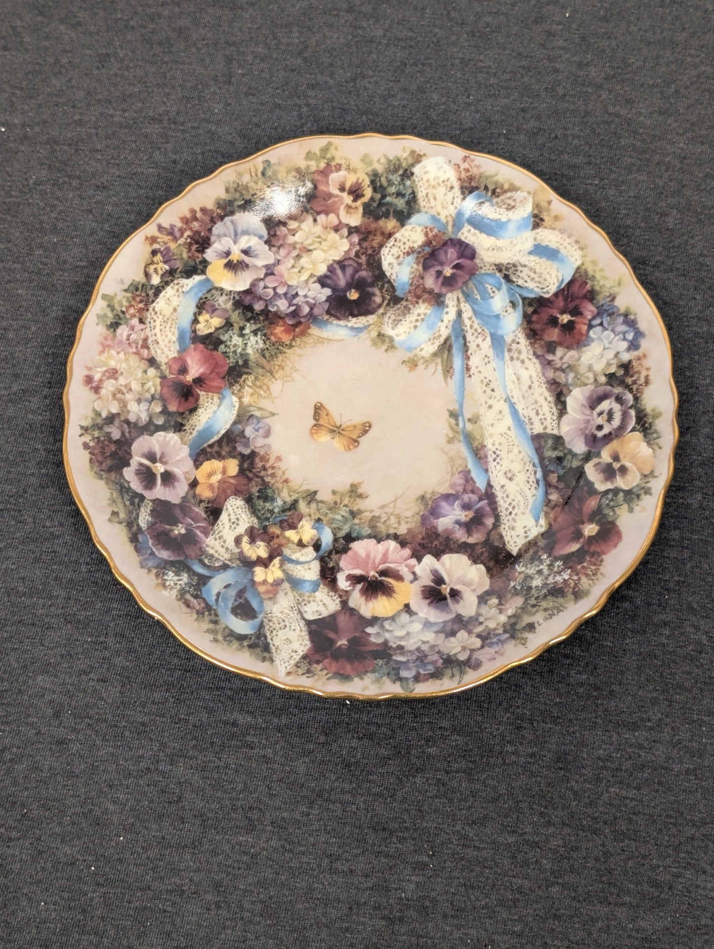 Porcelain plate featuring a wreath of pansies tied with a delicate blue and white lace ribbon.