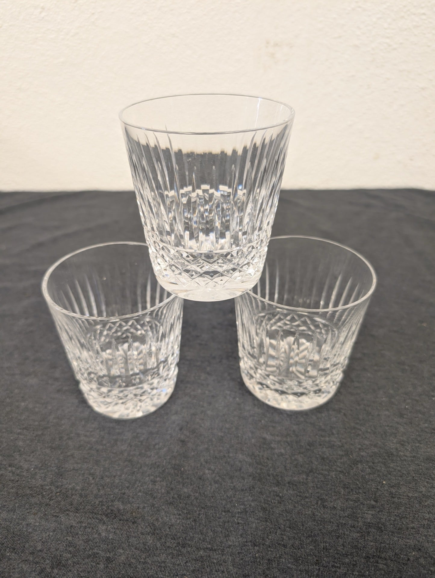 Three clear cut glass lowball tumblers stacked in a pyramid.