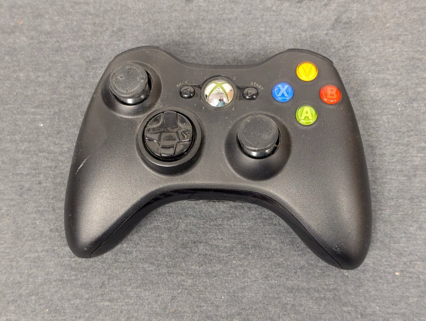 Black Xbox 360 controller with left thumbstick missing rubber