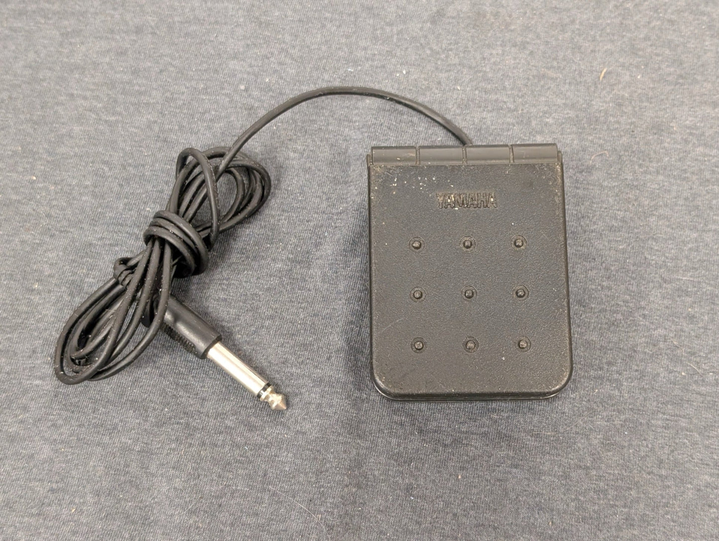 Black Yamaha FC5 sustain pedal with 1/4 inch cable on grey background