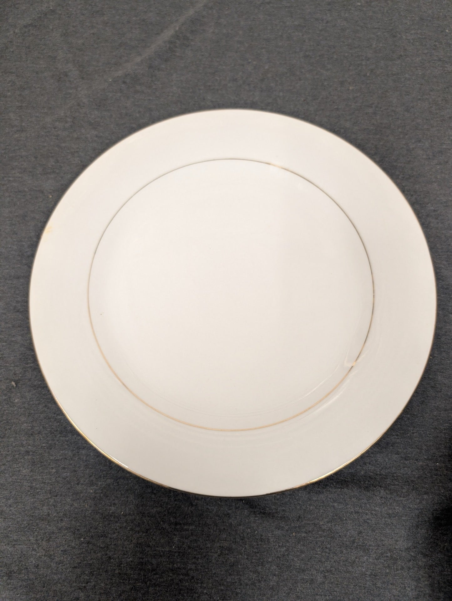 Front view of a white Sakura Classic Gold dinner plate with gold rim.