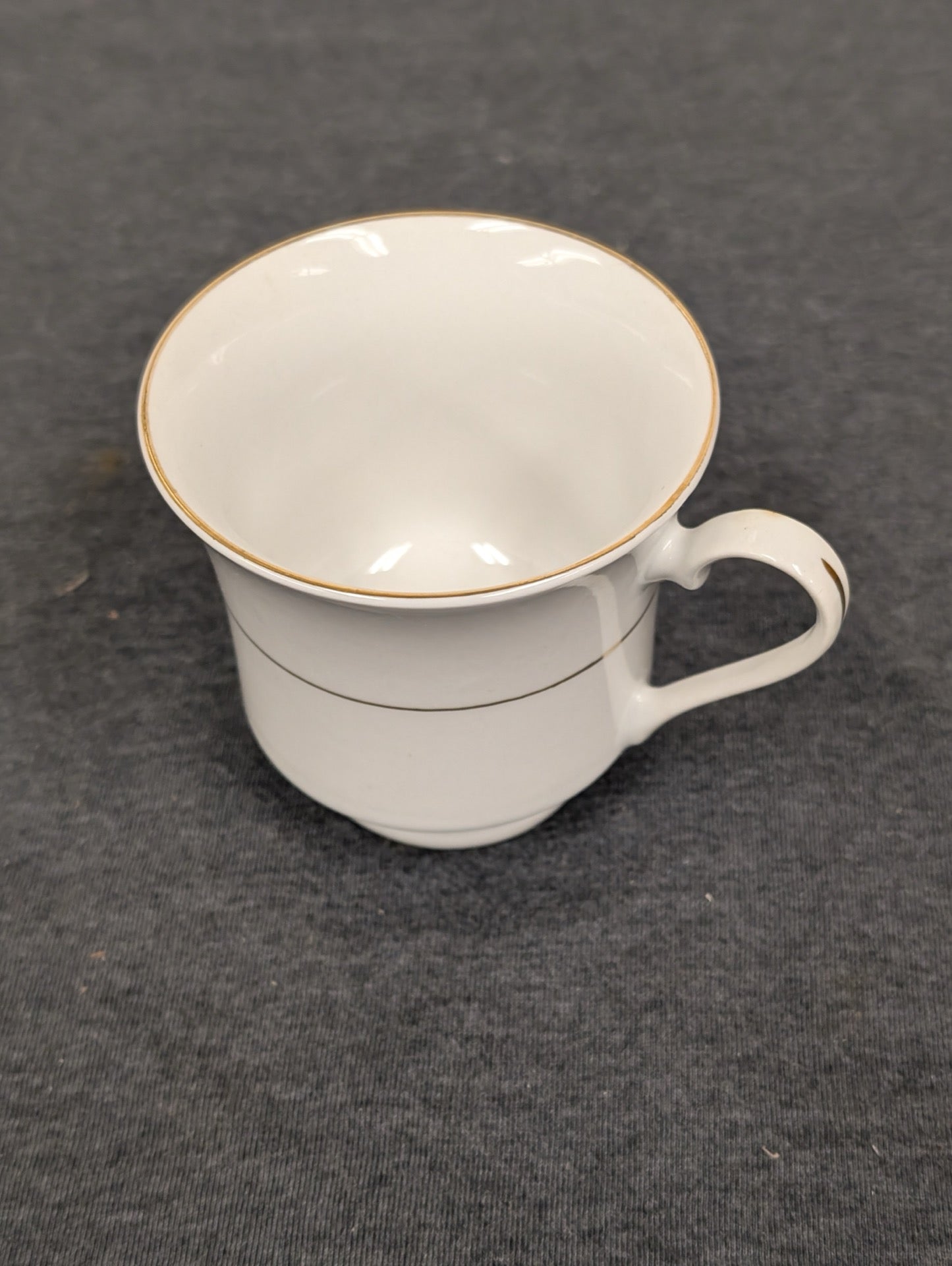 Top-down angled view of an empty white Sakura teacup with gold rim
