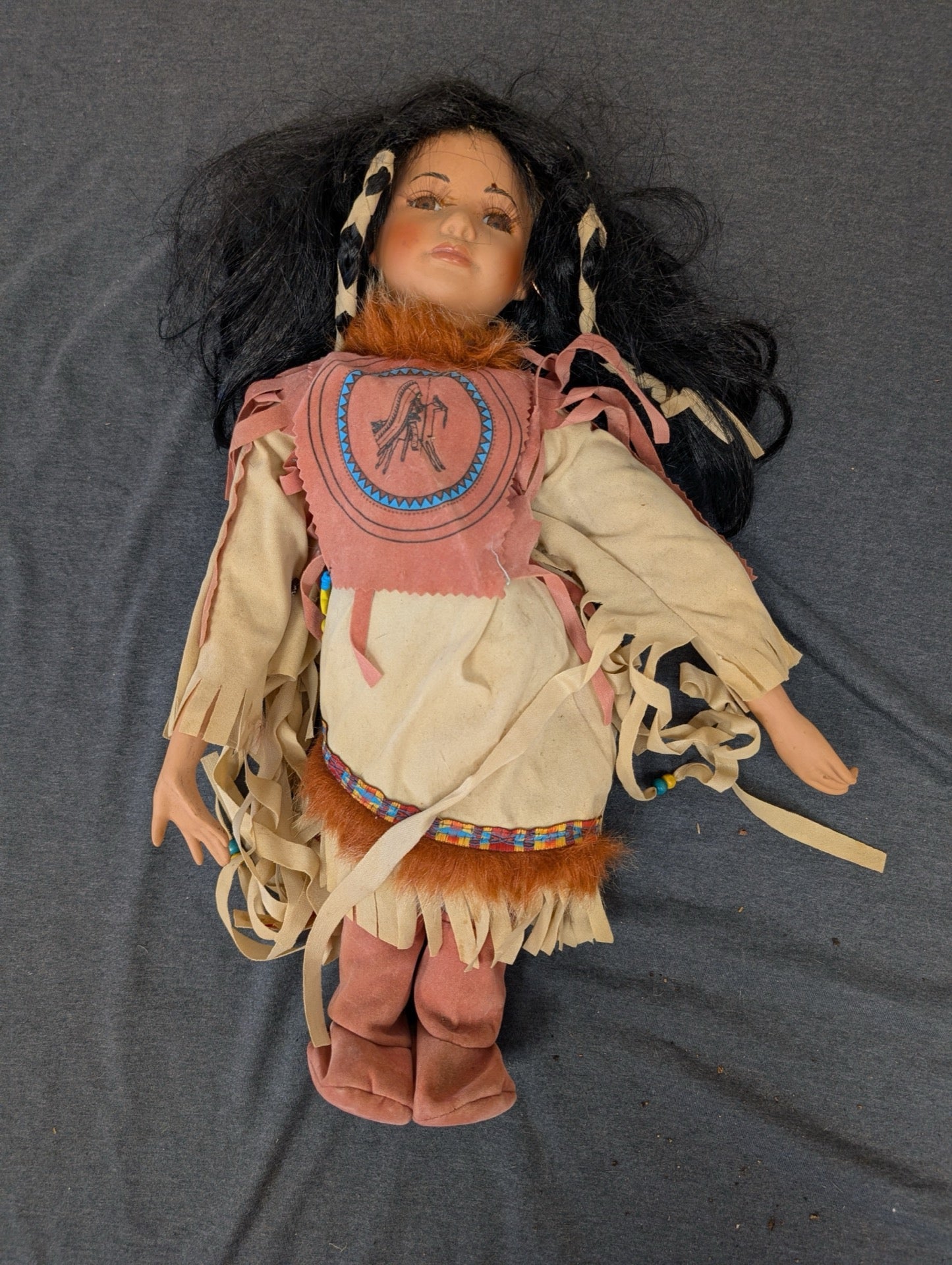 Native American style porcelain doll with dark hair and fringed faux leather dress