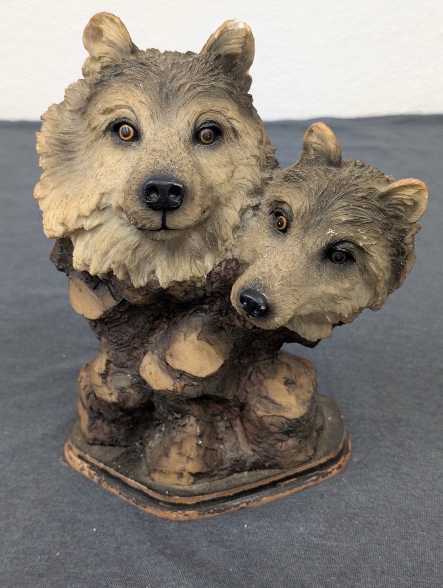 Resin bust featuring two detailed wolf heads emerging from a wooden textured base