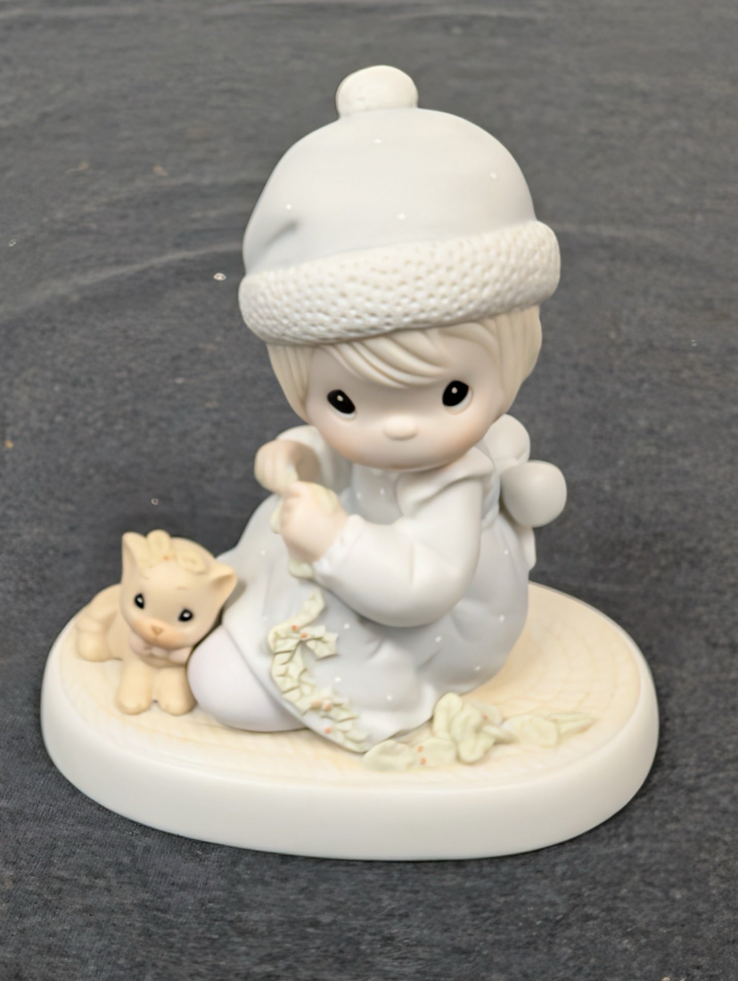 Precious moments porcelain figurine of a young girl in winter clothes sitting with a yellow kitten.