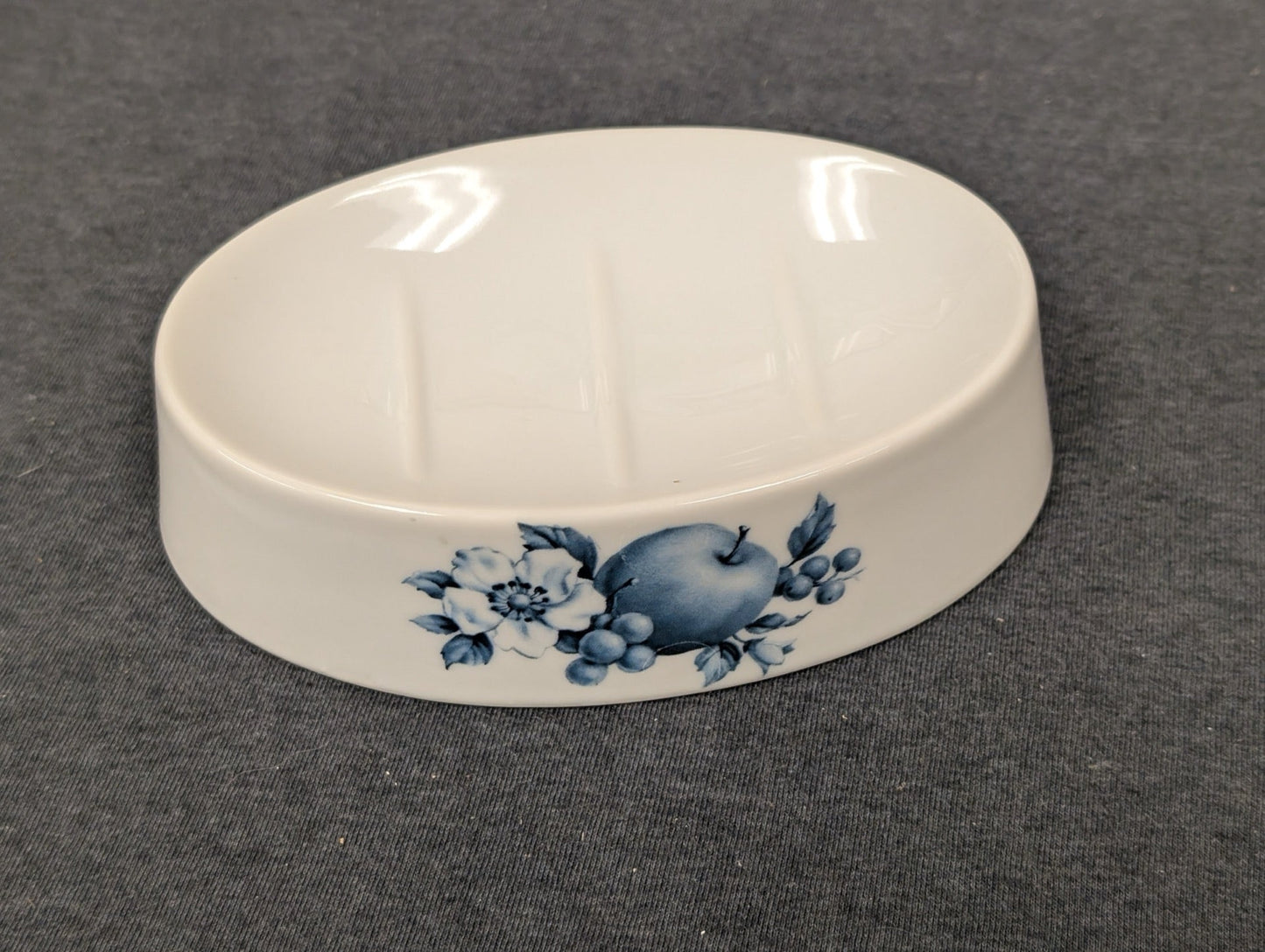 White ceramic soap dish featuring a blue apple and floral illustration.