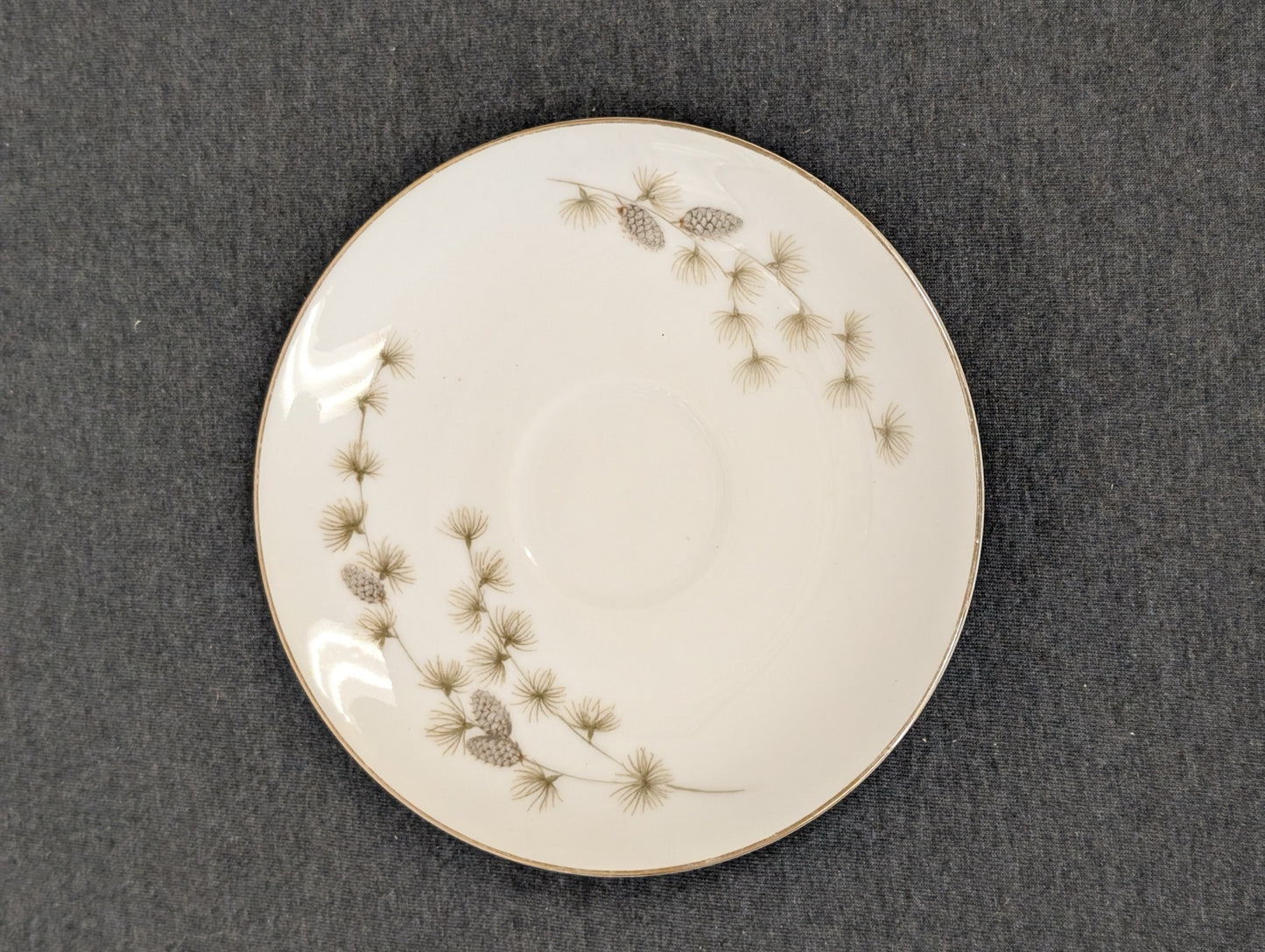 Top view of a vintage Mikasa Sequoia saucer with cup indentation and pinecone design