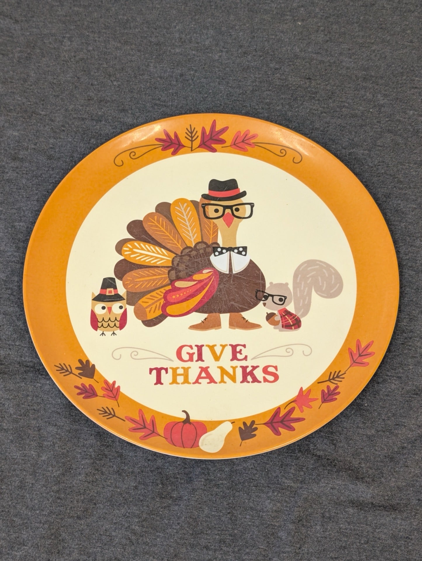 Round orange and cream plate reading Give Thanks with a turkey, owl and squirrel wearing glasses and hats