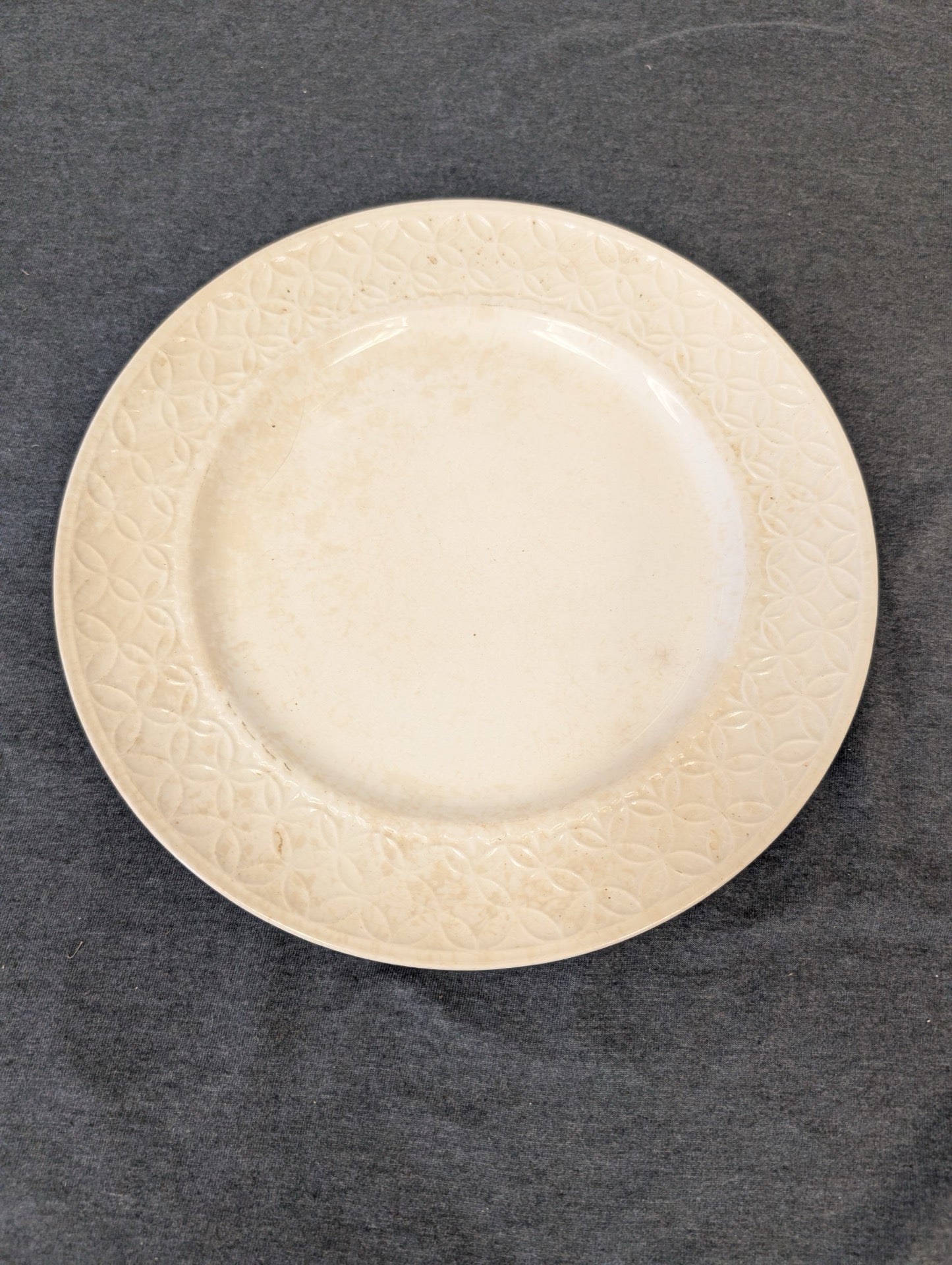 Cream plate with an embossed geometric circular pattern around the rim.