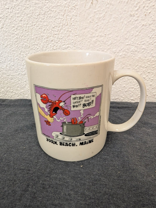 White mug with a cartoon of a lobster being put into a boiling pot by a chef.