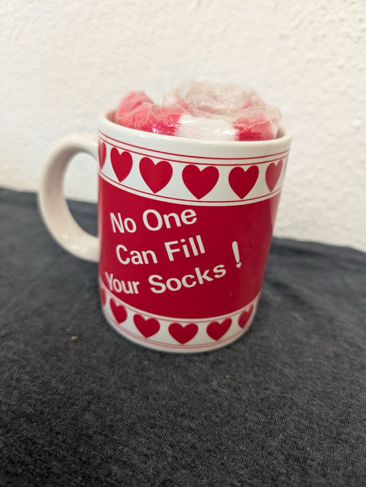 Red ceramic mug with white text saying No One Can Fill Your Socks and rolled socks inside.