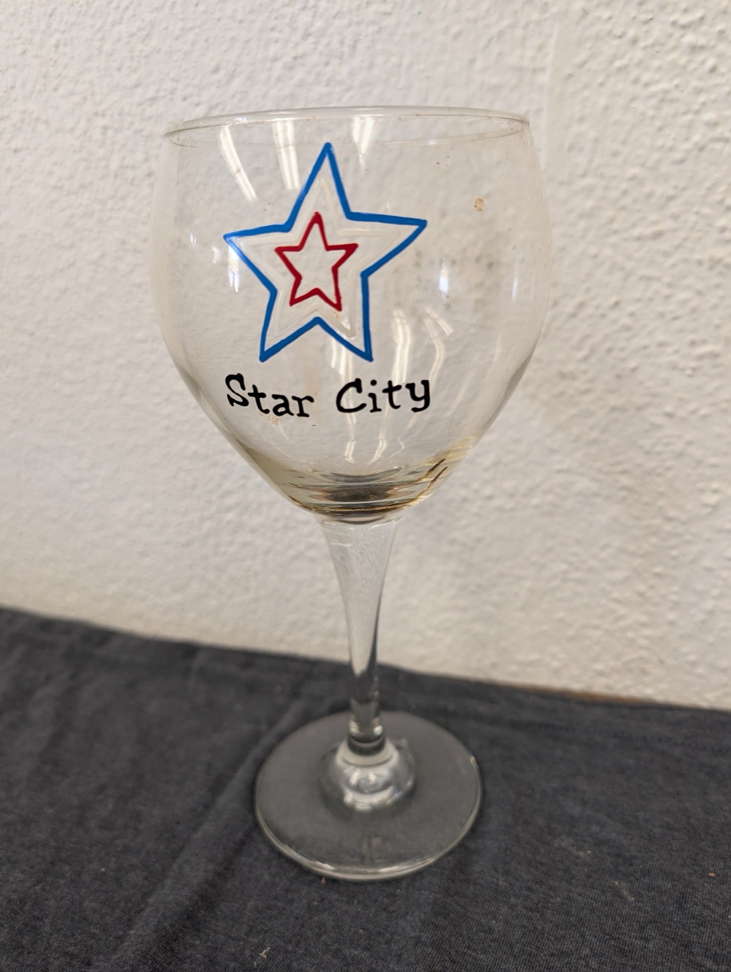 Clear stemmed wine glass with a blue and red star logo and Star City text.