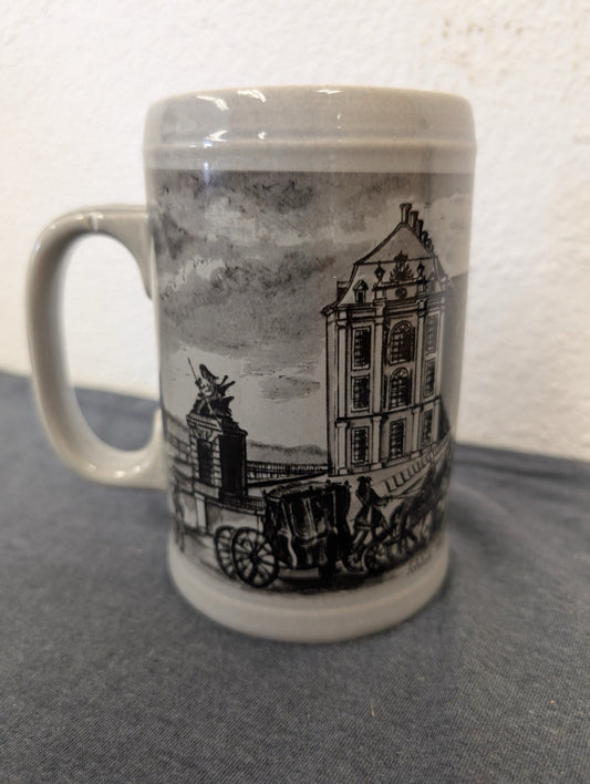 Greyish ceramic stein with a detailed black ink style drawing of a historical palace and carriage.