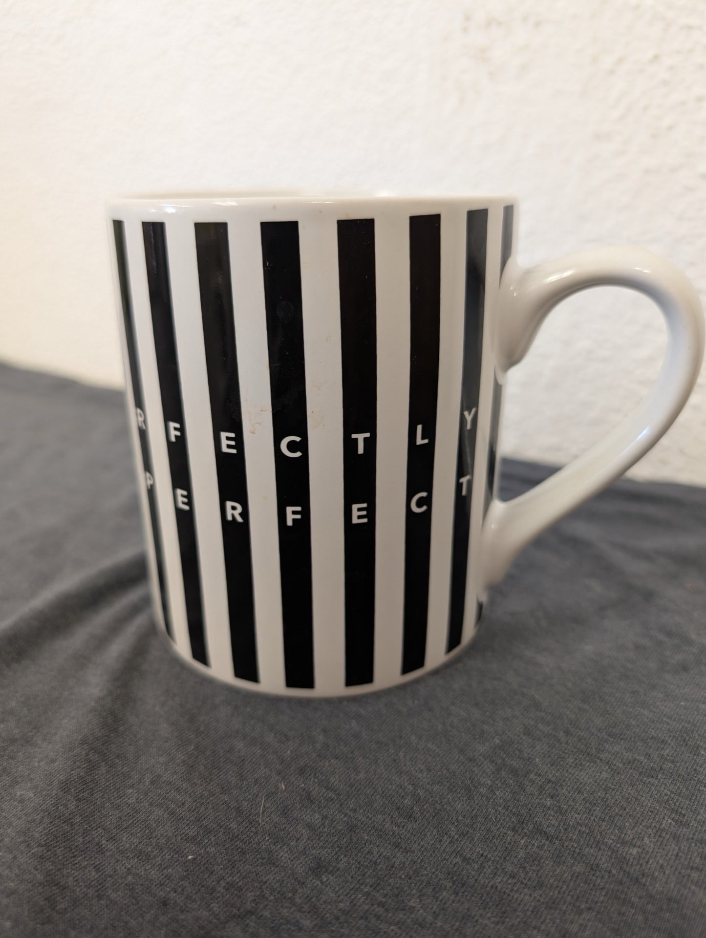 White ceramic mug with black vertical stripes and the text Perfectly Perfect seamlessly integrated into the pattern.