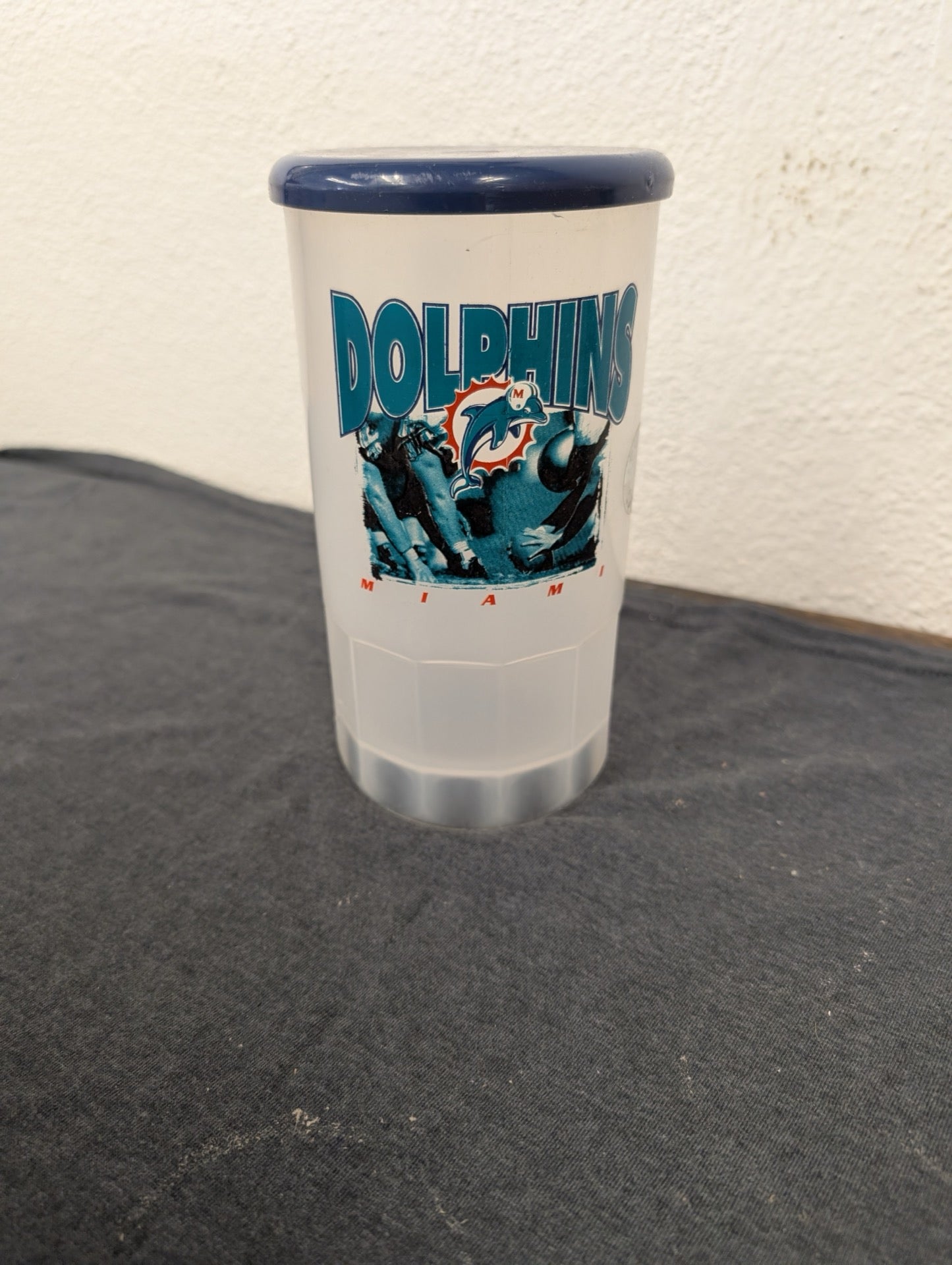 Translucent plastic tumbler with a blue lid and a vintage Miami Dolphins football graphic.