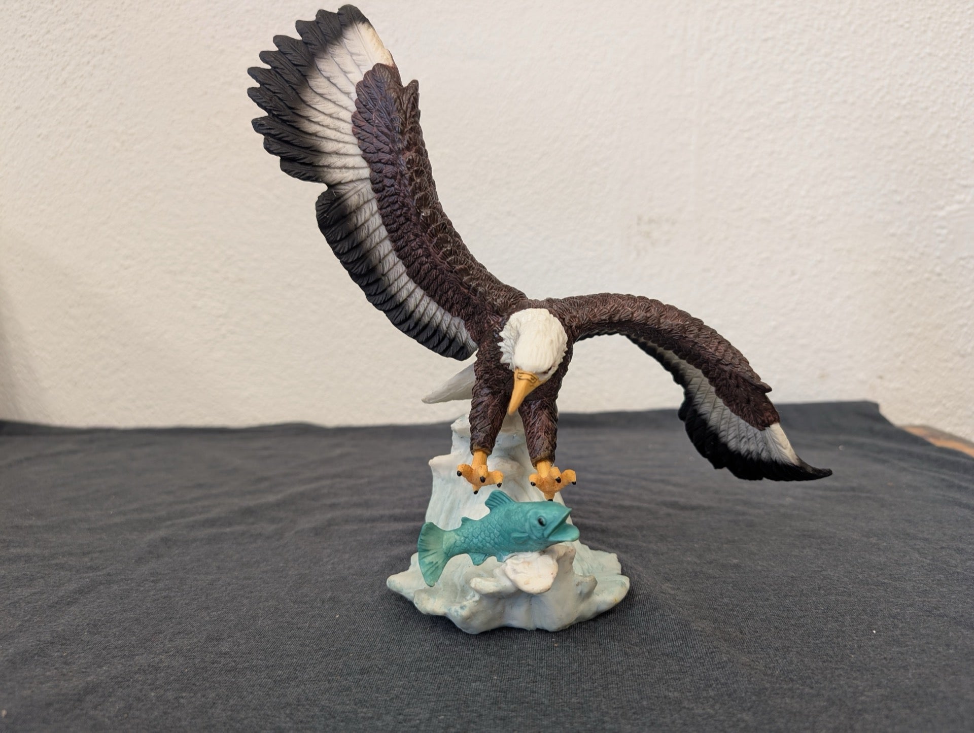 Resin figurine of a bald eagle swooping down to catch a teal fish