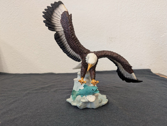 Resin figurine of a bald eagle swooping down to catch a teal fish
