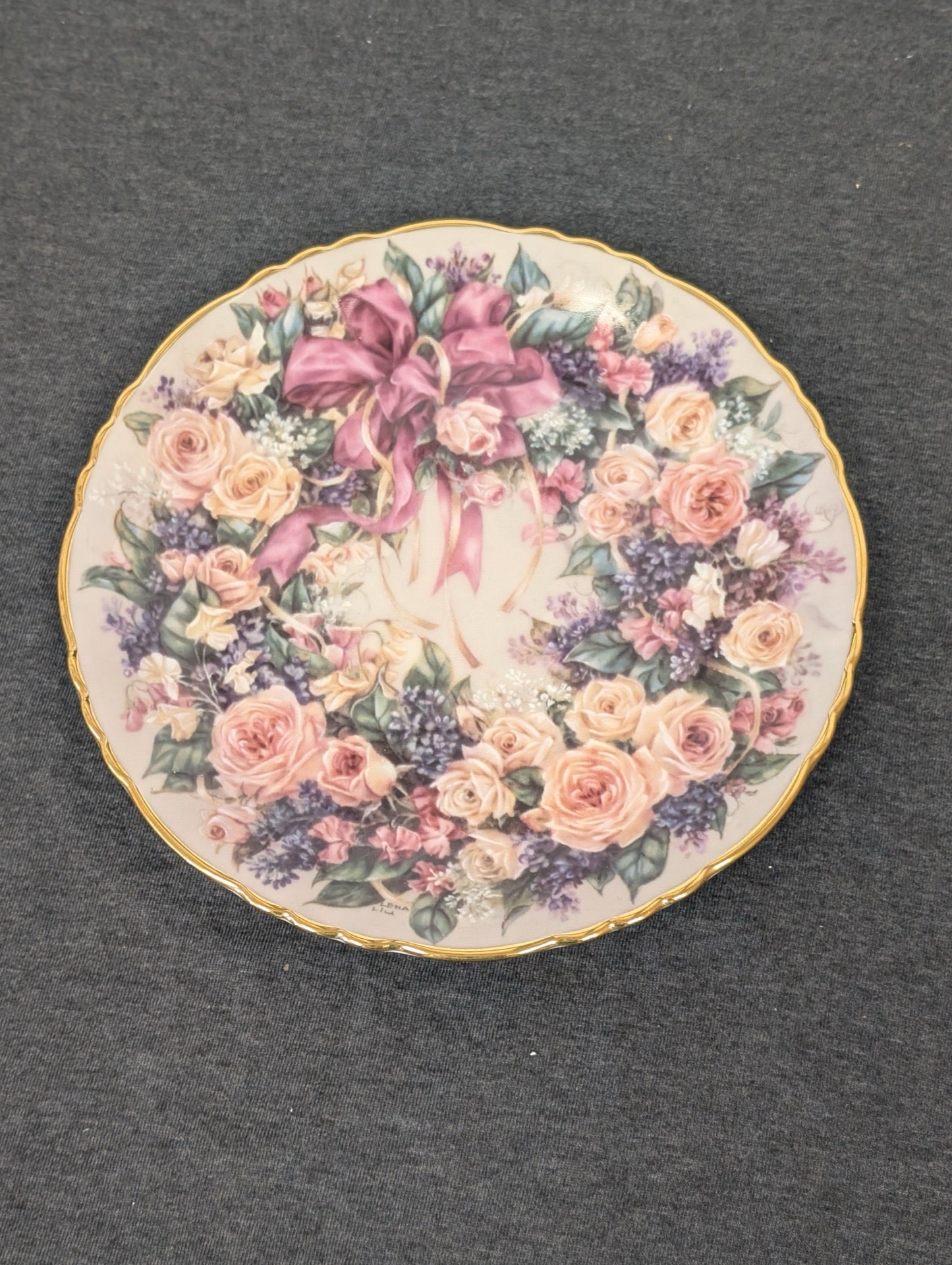 Porcelain plate showing a wreath of pink roses and lilacs tied with a large pink bow.