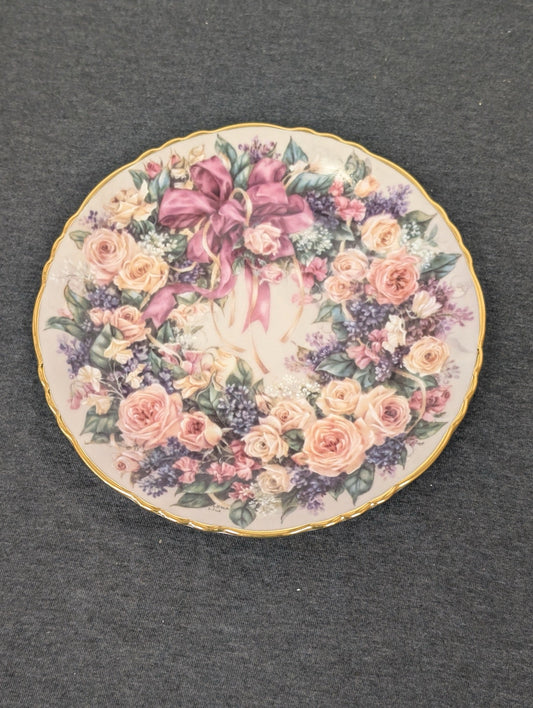 Porcelain plate showing a wreath of pink roses and lilacs tied with a large pink bow.