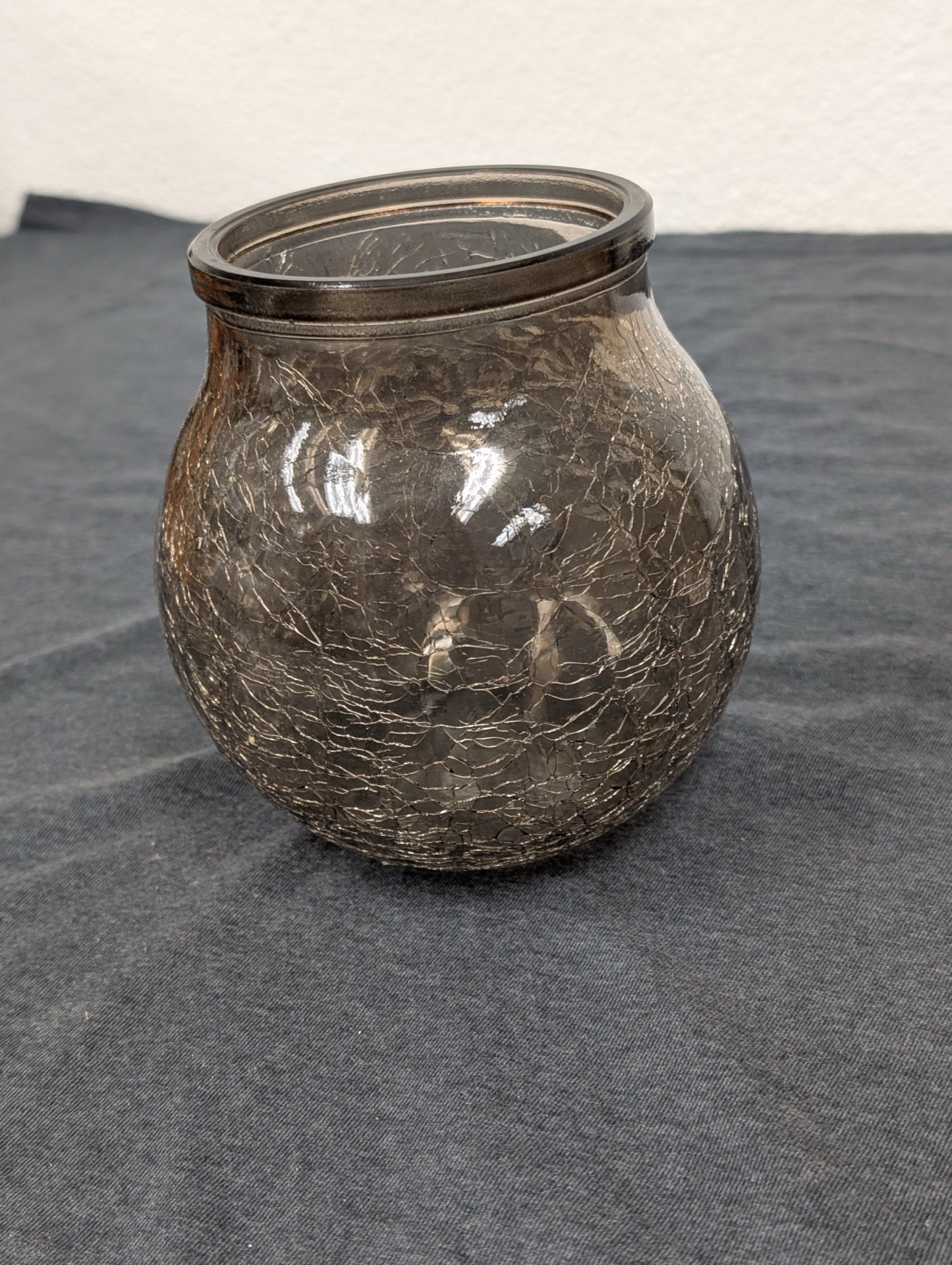 Round brown crackle glass jar or candle holder sitting on a dark surface.
