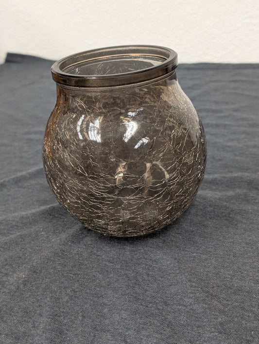 Round brown crackle glass jar or candle holder sitting on a dark surface.
