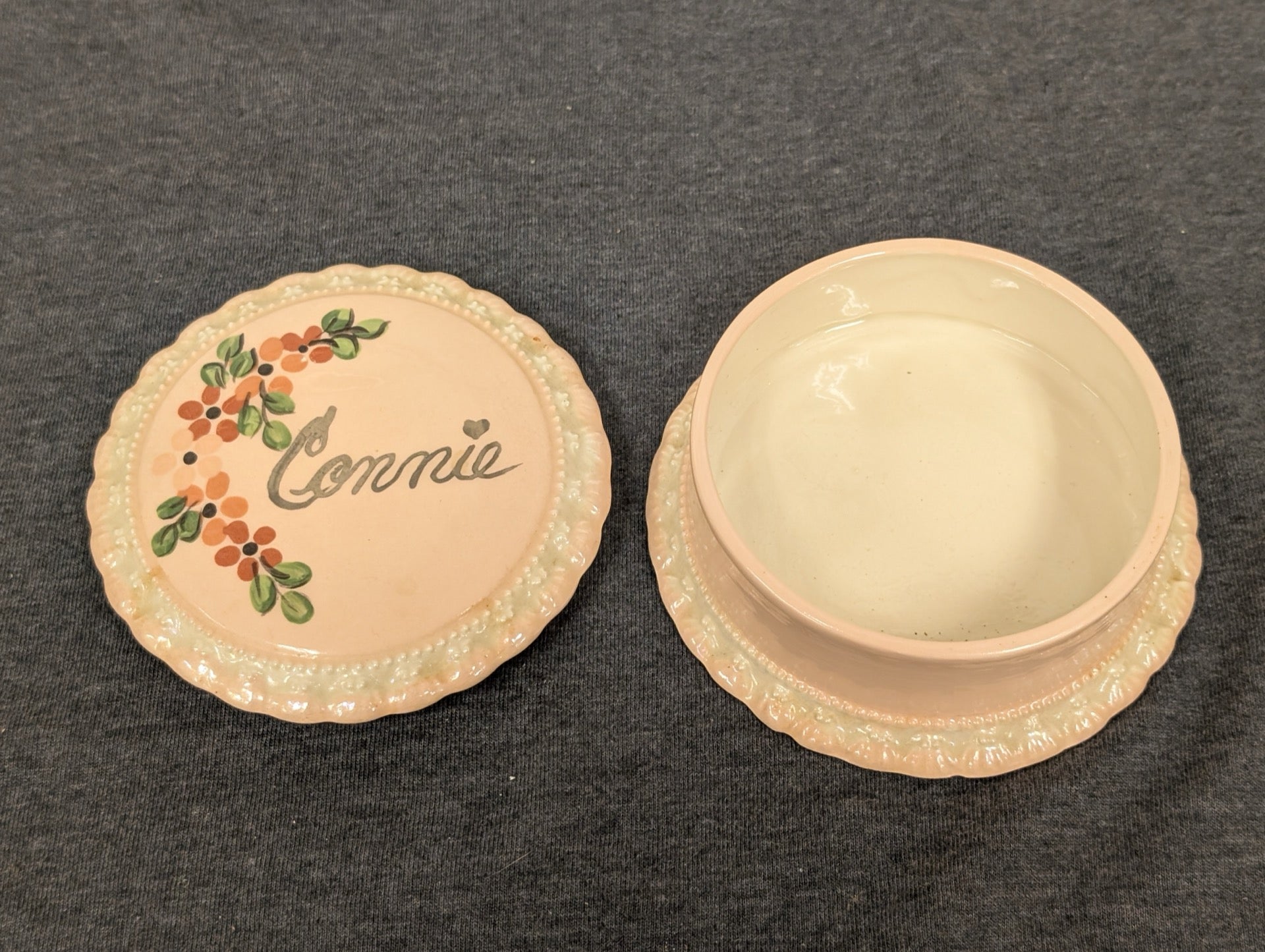 Open pink ceramic trinket box with the lid showing the name Connie and painted flowers.