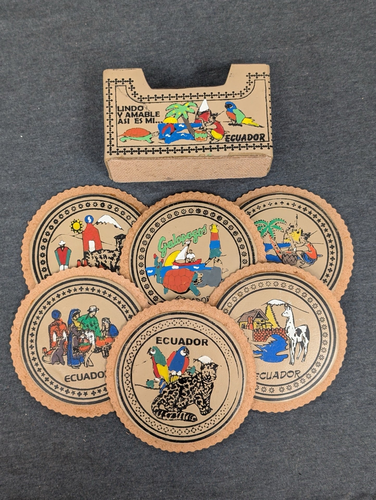 Set of six round leather coasters painted with Ecuadorian scenes and a matching holder.