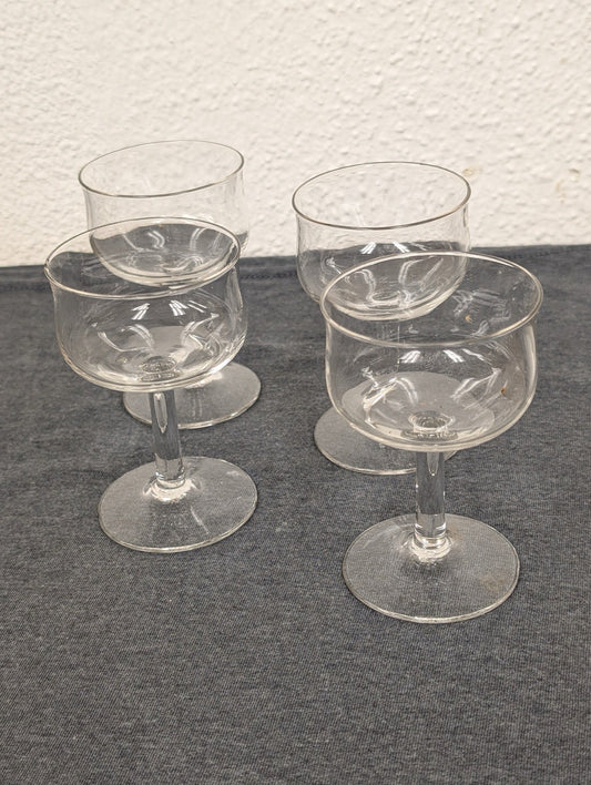 Four clear glass stemmed glasses with tulip-shaped bowls clustered together.