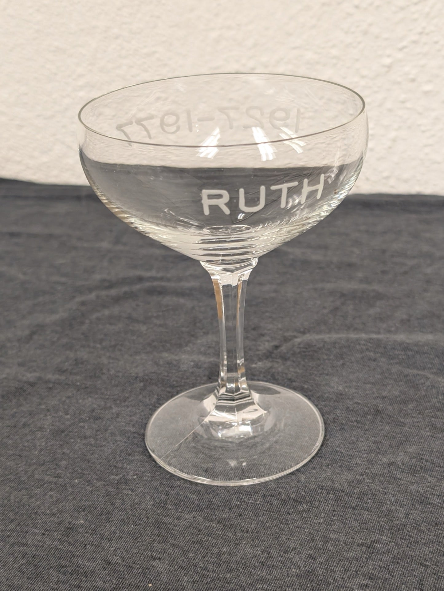 Single clear coupe glass with RUTH and 1927-1977 etched into the side.