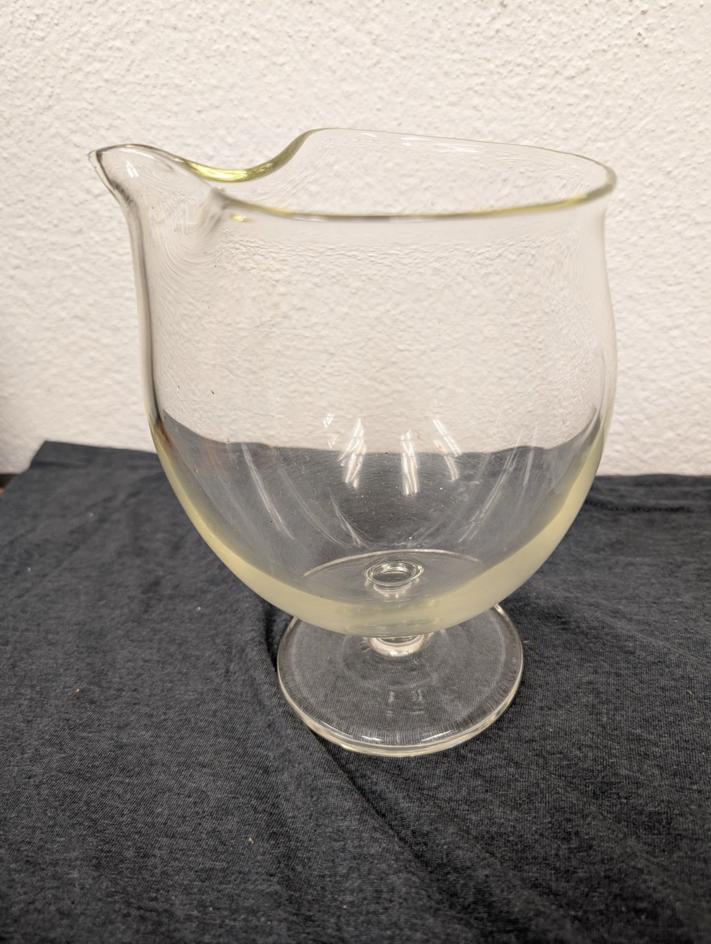 Clear glass pitcher or creamer with a delicate spout and a short stem base.