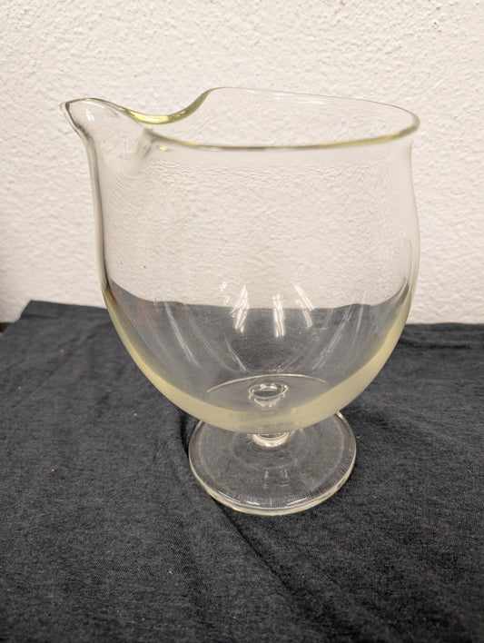 Clear glass pitcher or creamer with a delicate spout and a short stem base.