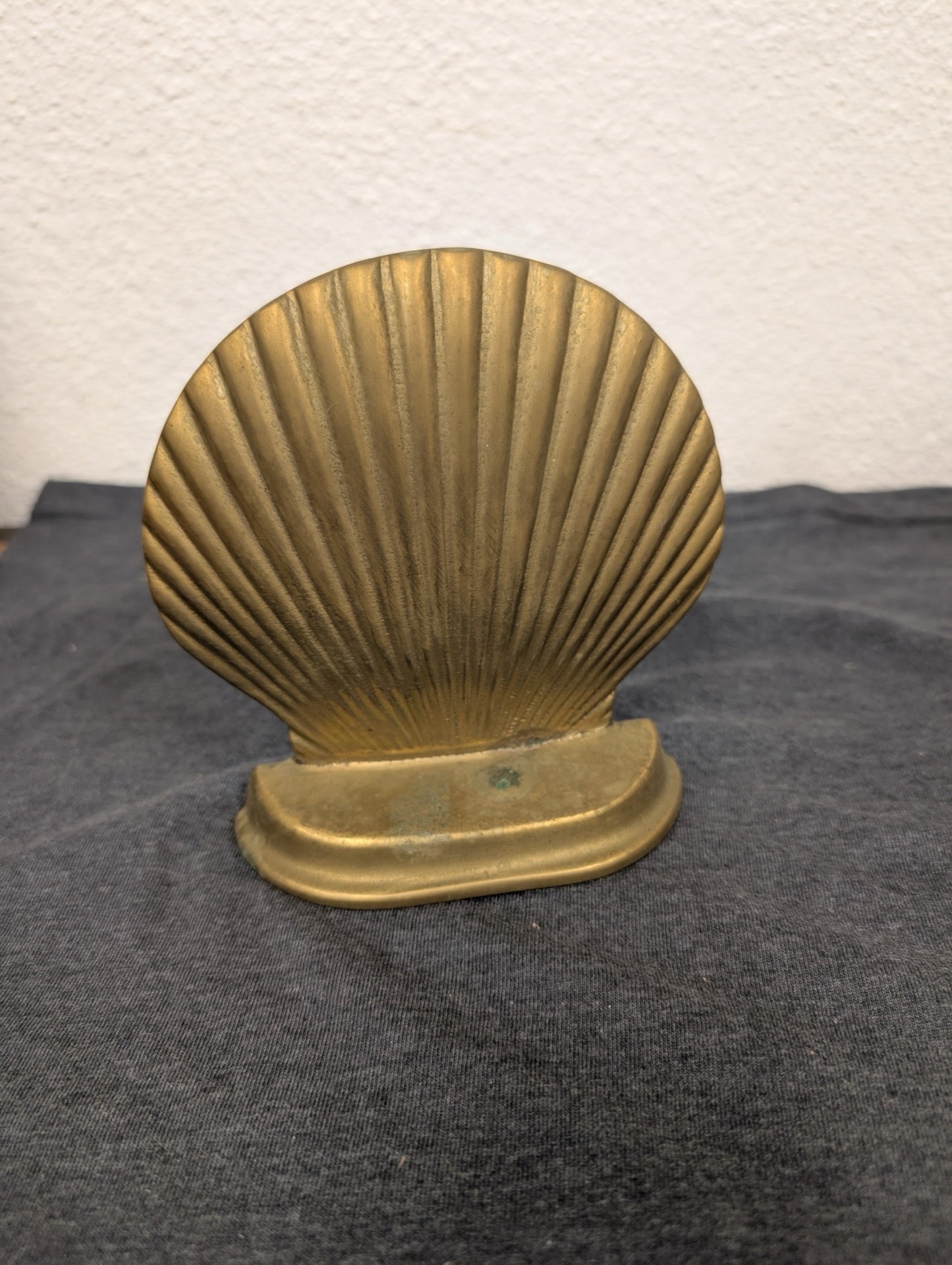 Solid brass holder shaped like a scallop shell resting on a curved base.