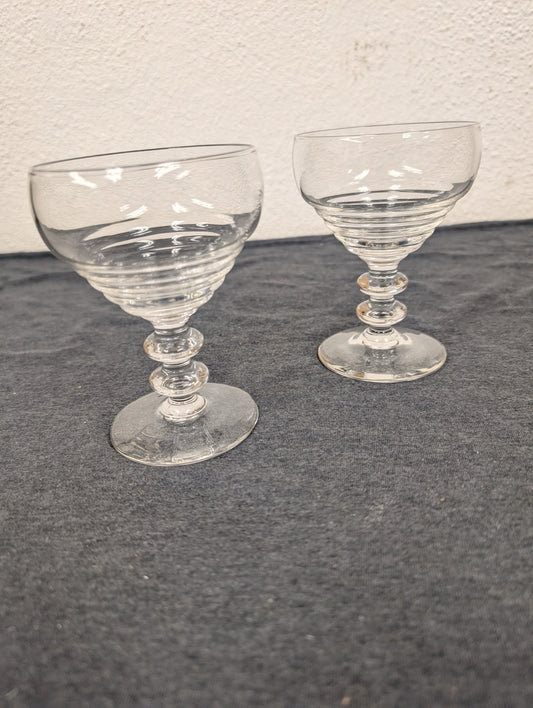 Two ribbed clear glass coupe cocktail glasses with tiered double-ball stems.
