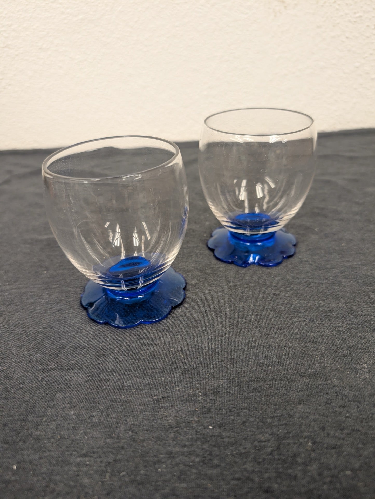 Two small clear glasses with a bright cobalt blue, flower-petal shaped base.