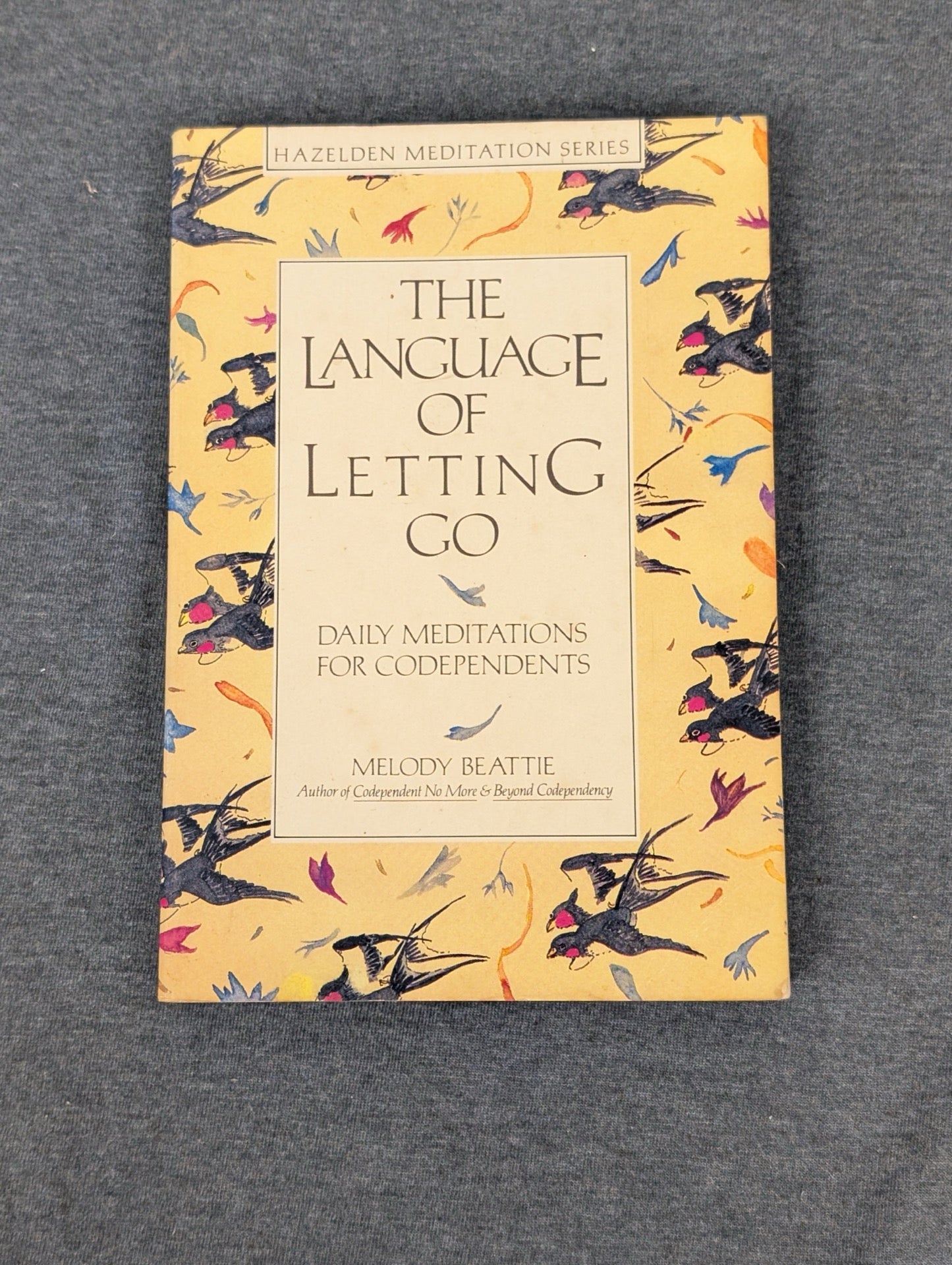 Cover of The Language of Letting Go by Melody Beattie with a yellow bird pattern.
