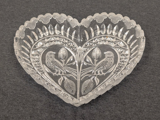 Clear vintage pressed glass heart-shaped bowl featuring an embossed bird and leaf design.