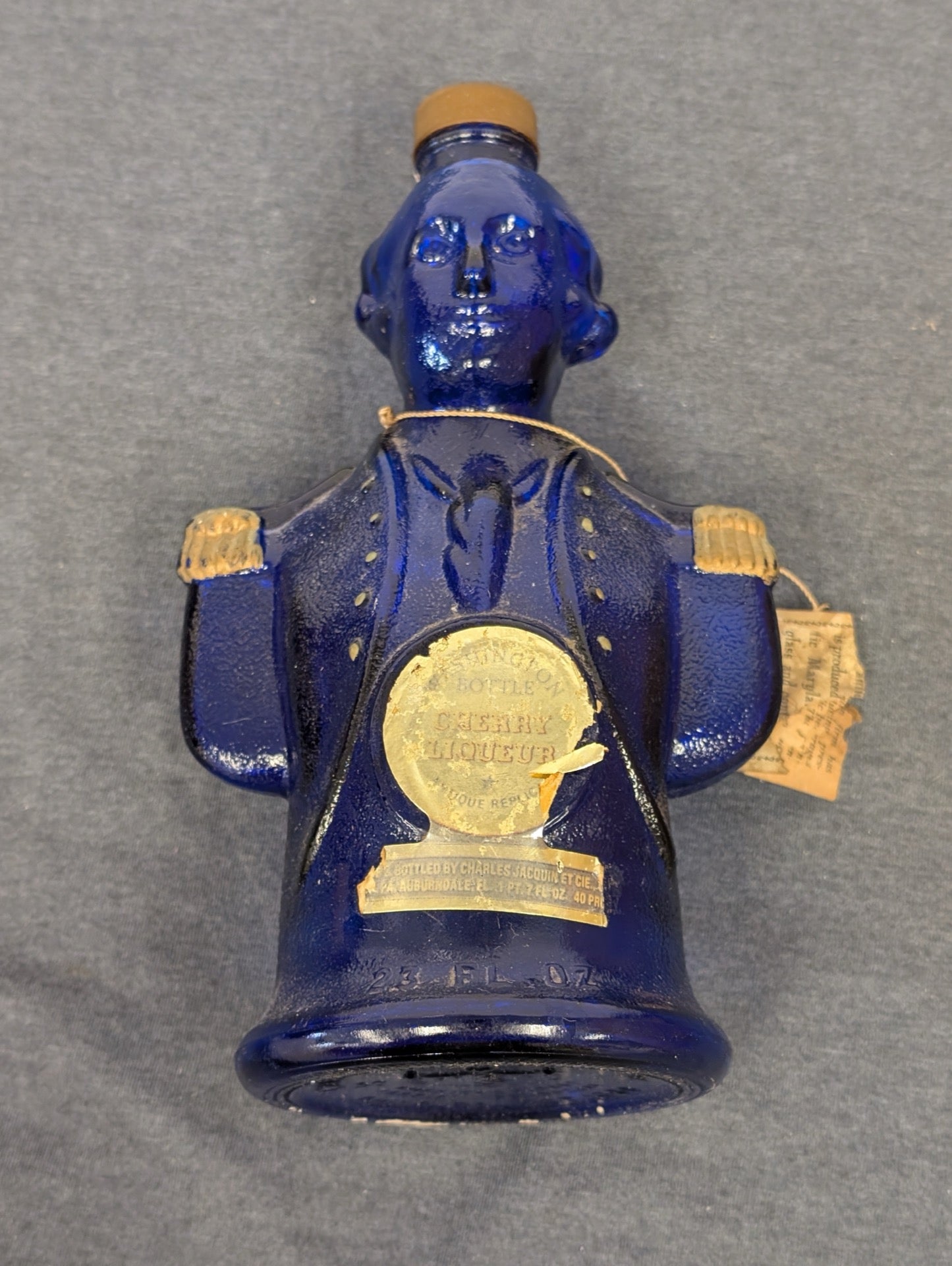 Blue glass figural bottle shaped like George Washington with original paper labels.