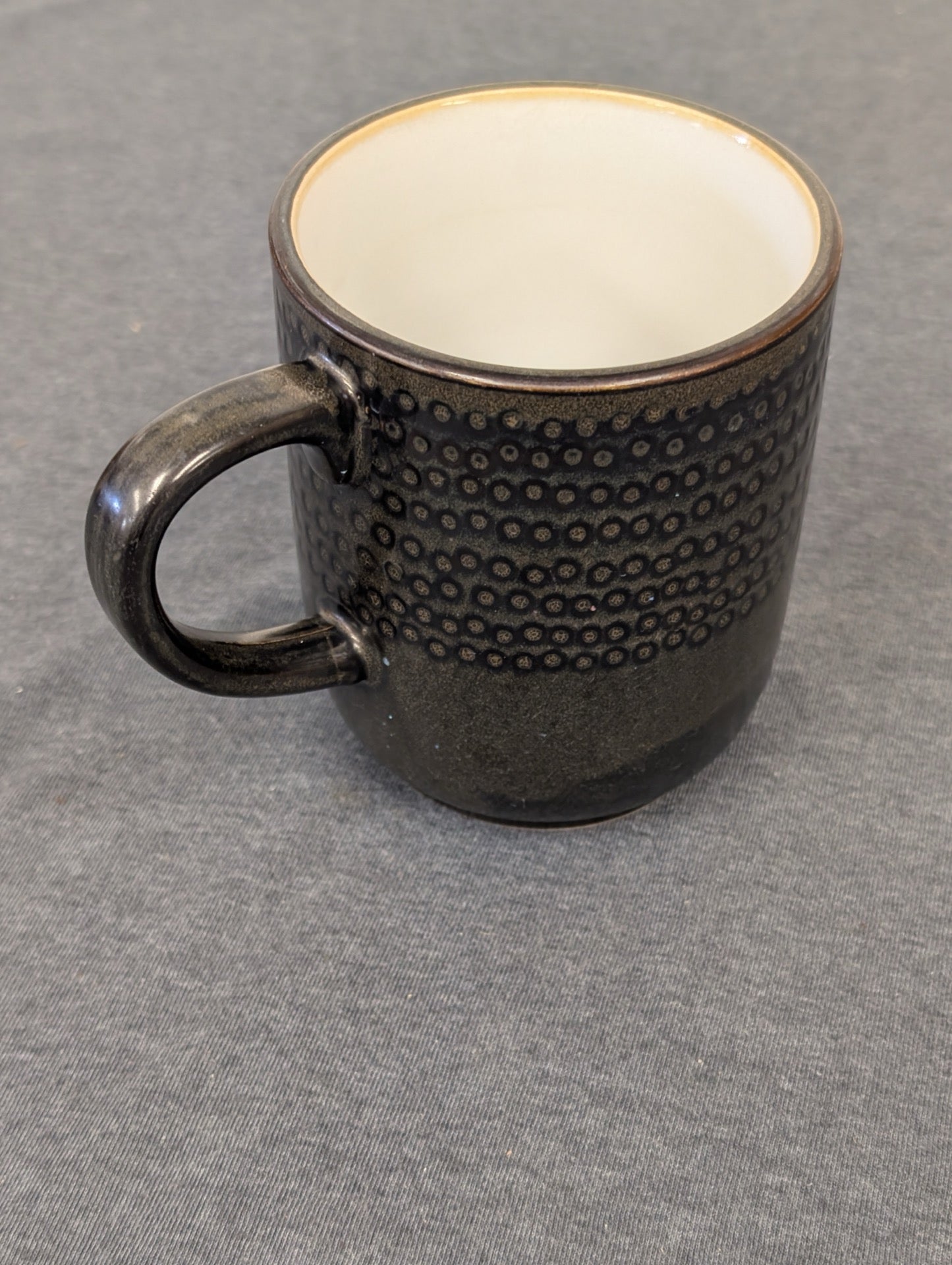 Dark brown glazed stoneware mug with a band of raised circular textures.