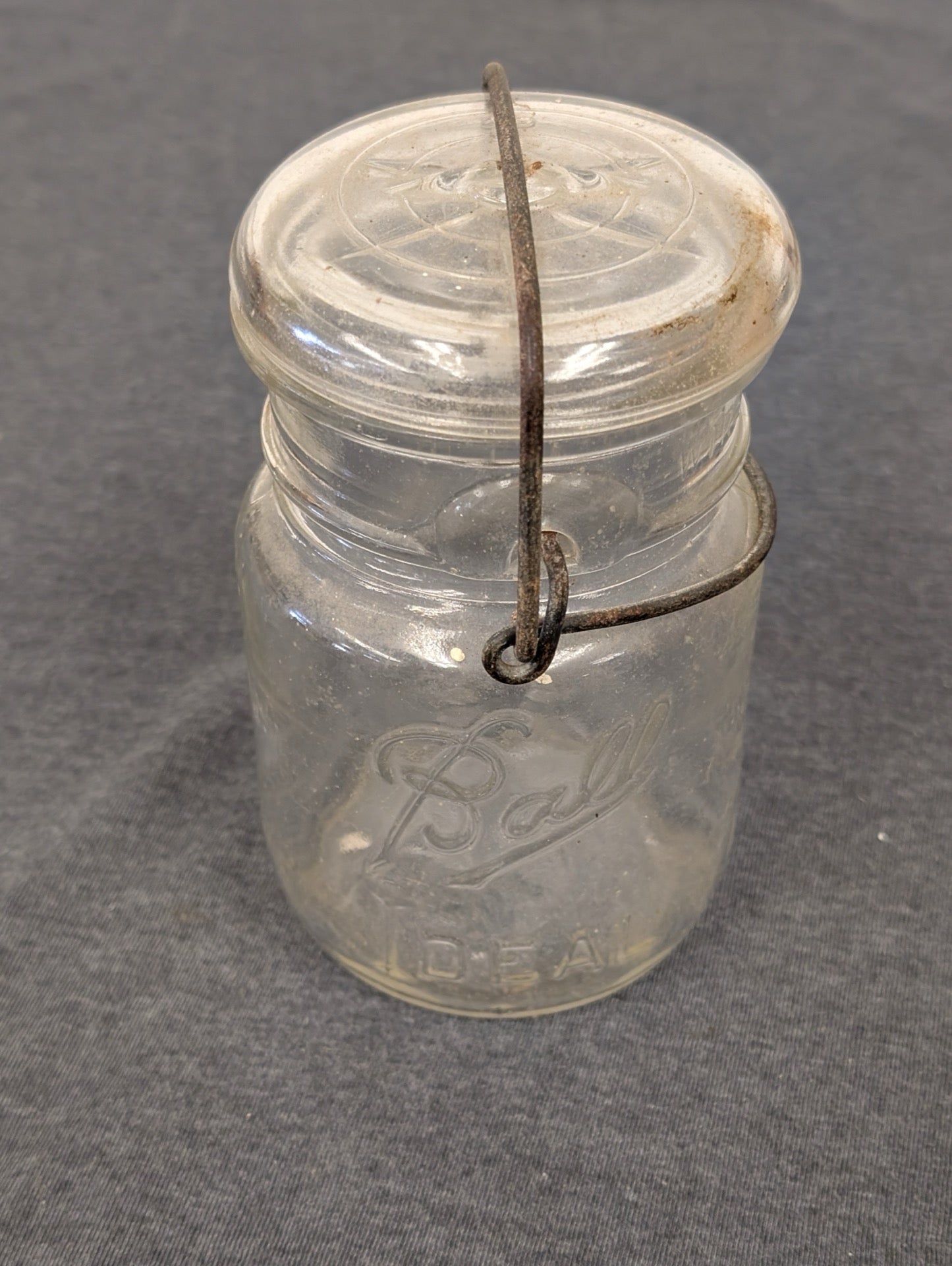 Clear glass Ball Ideal jar with a glass lid secured by a rusted metal wire bail.