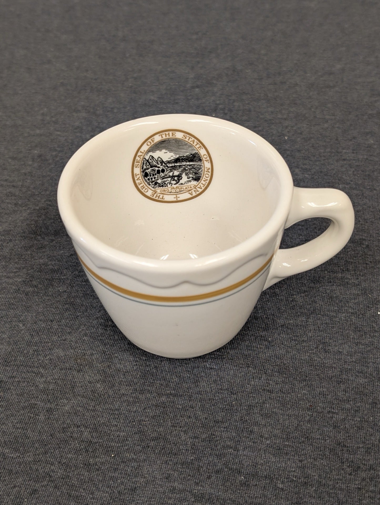 Heavy white ceramic mug with The Great Seal of the State of Montana inside the rim.