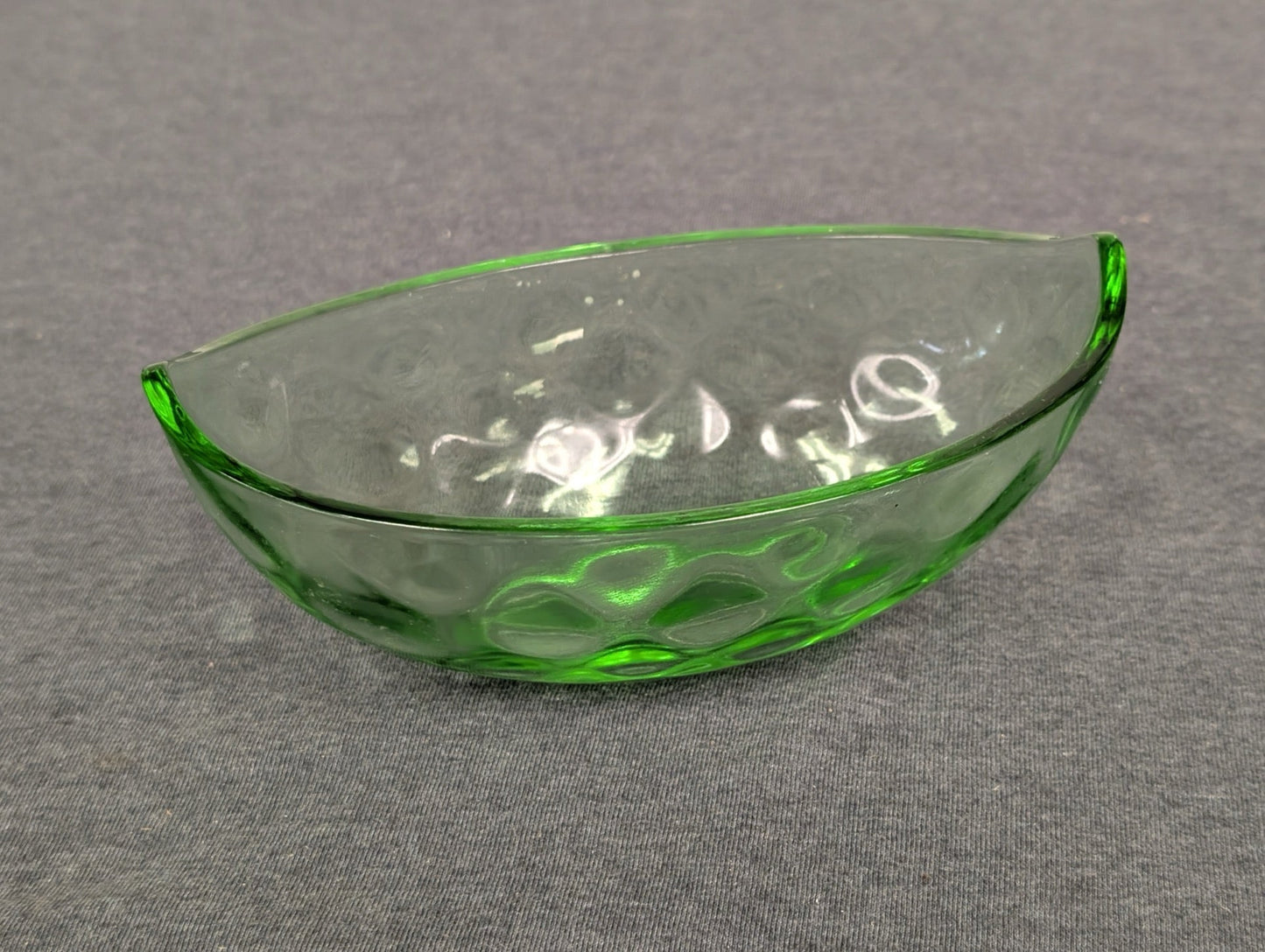 Half-moon shaped green glass bowl with a dimpled texture.