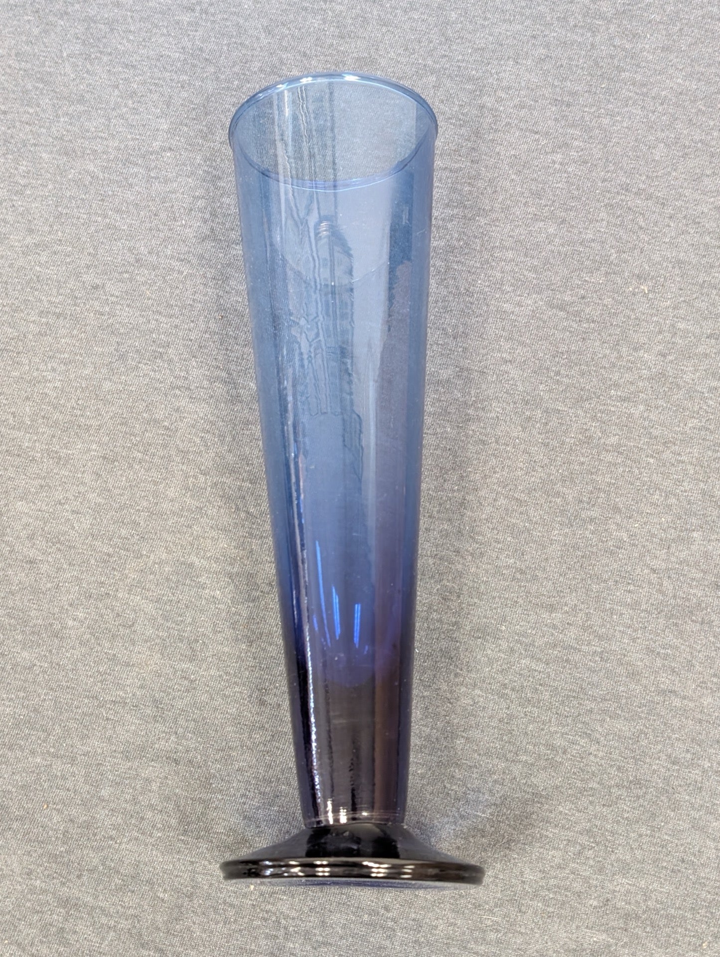 Tall, slender blue glass flute with a flat, dark glass base.