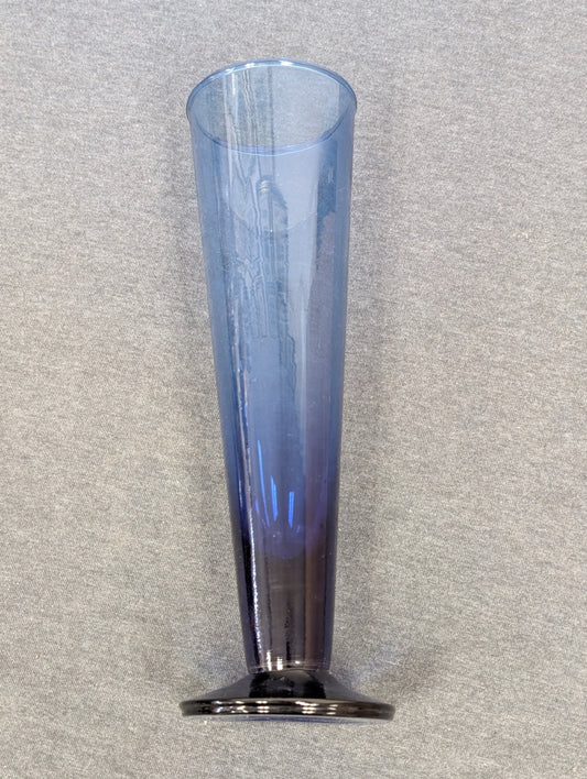 Tall, slender blue glass flute with a flat, dark glass base.