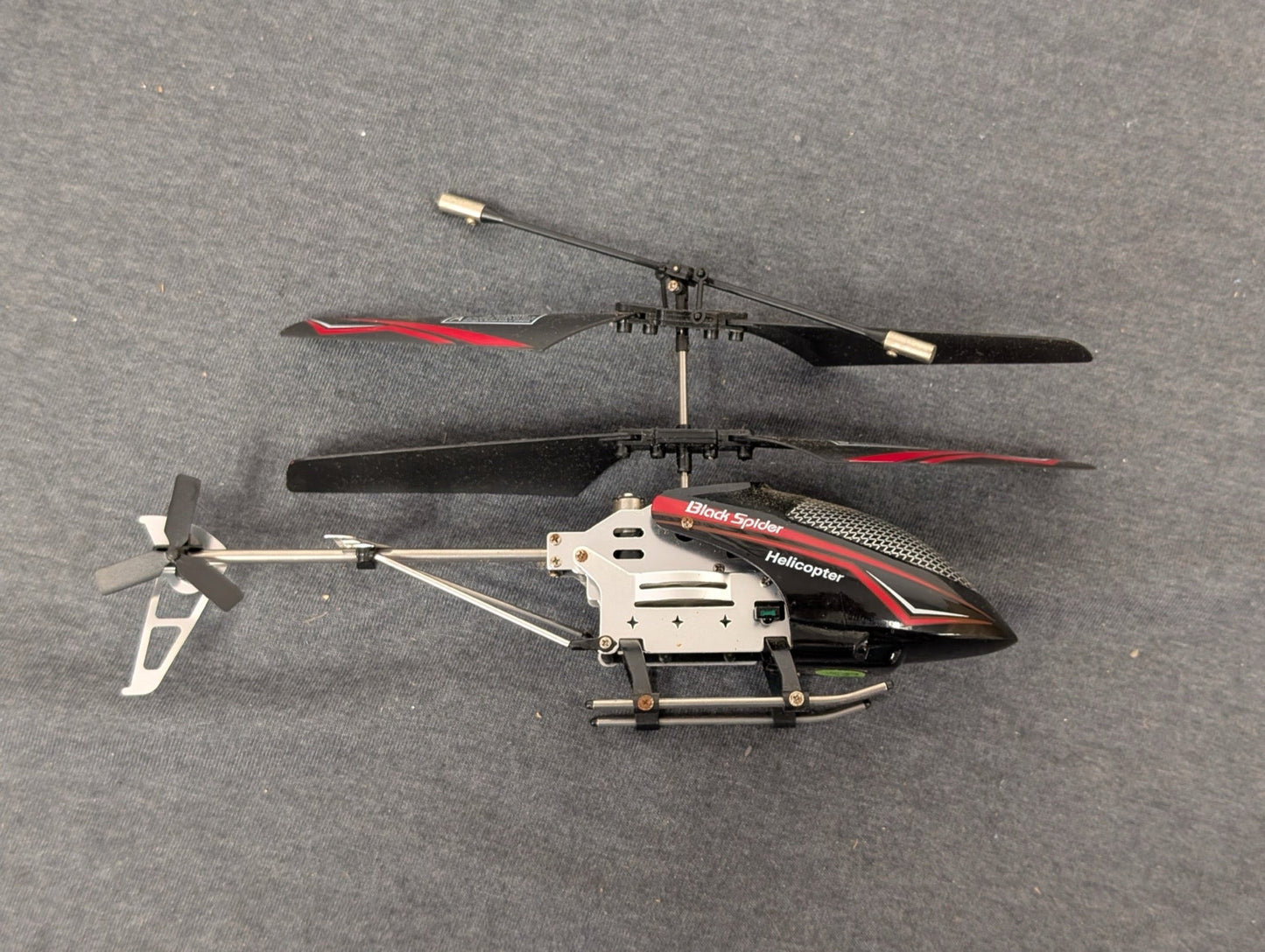Black and red Black Spider RC helicopter lying on its side
