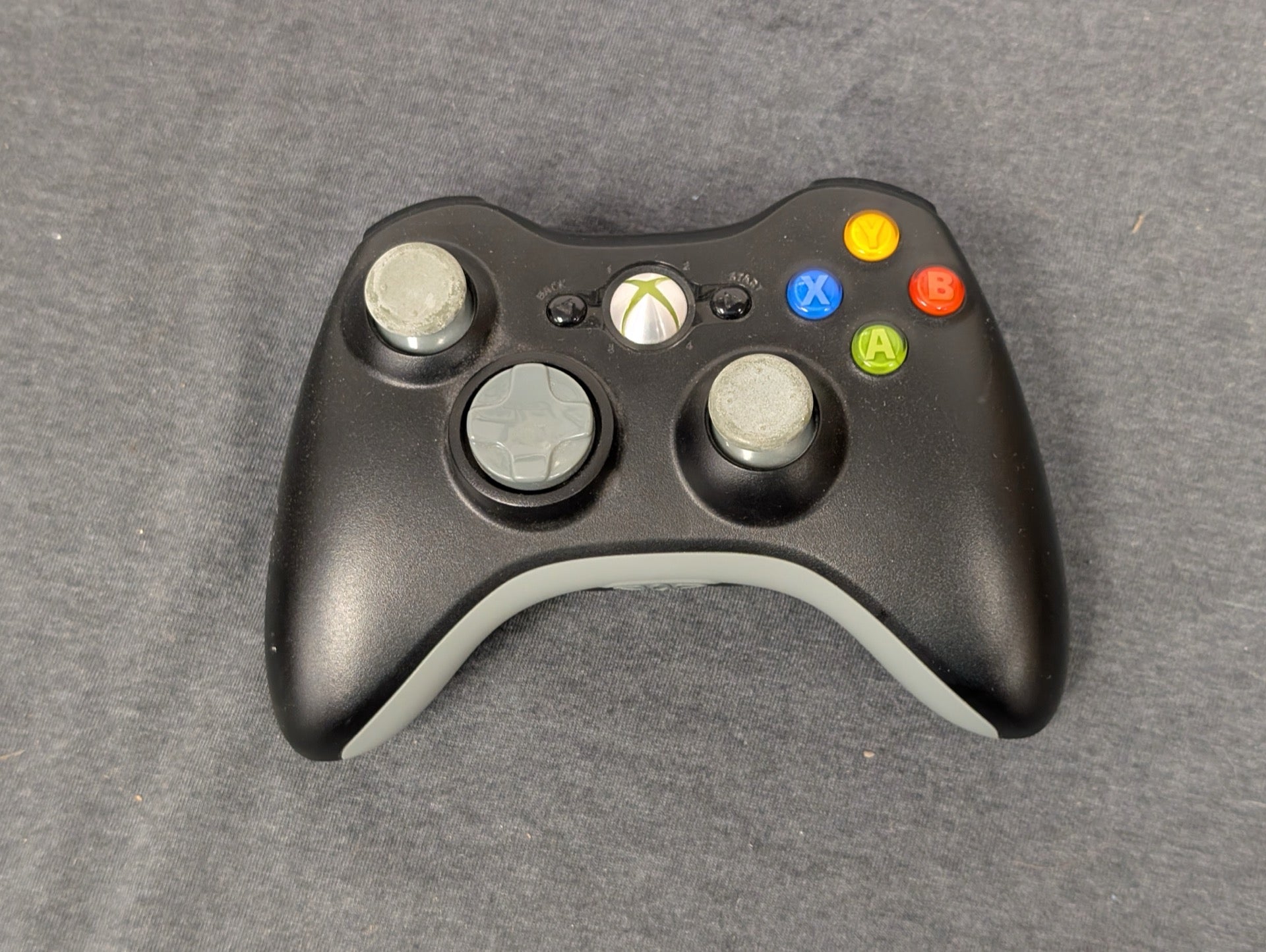 Black Xbox 360 controller with worn grey analog sticks