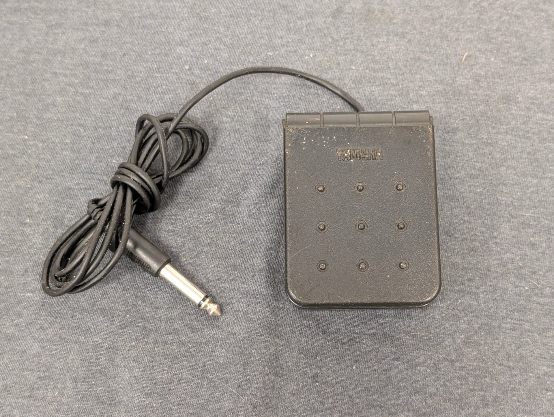 Black Yamaha FC5 sustain pedal with 1/4 inch cable on grey background