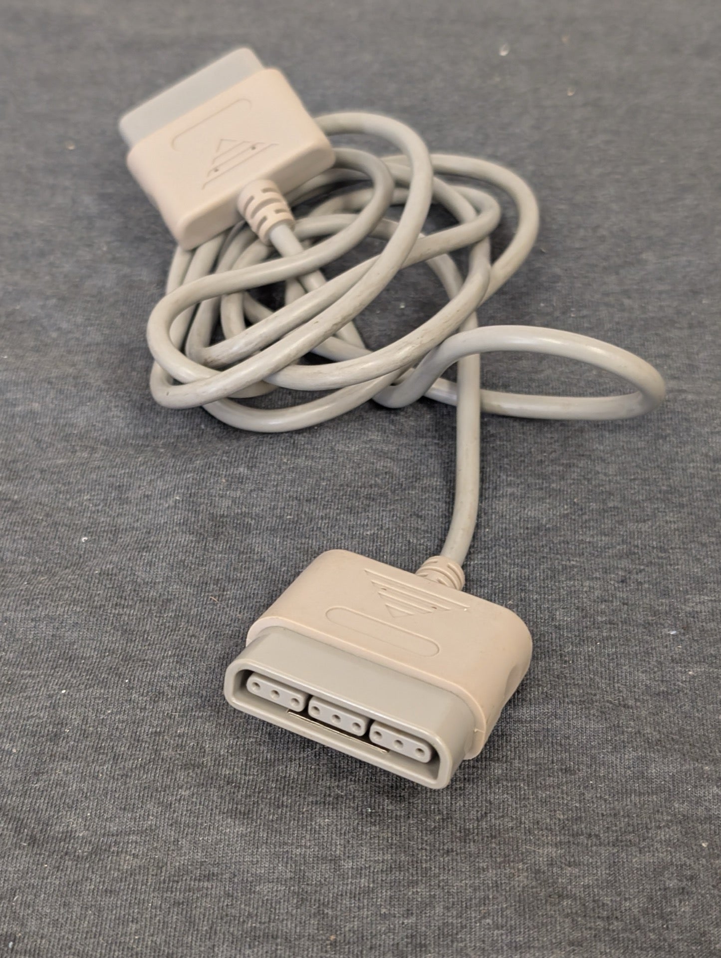 Grey Super Nintendo controller extension cable coiled on grey background