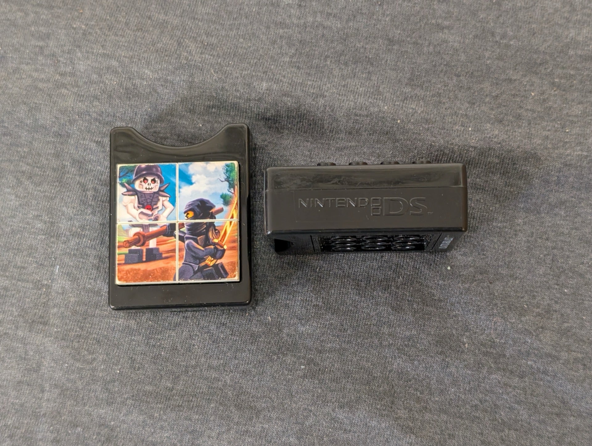 Two black Nintendo DS game holders, one showing a Lego Ninjago image